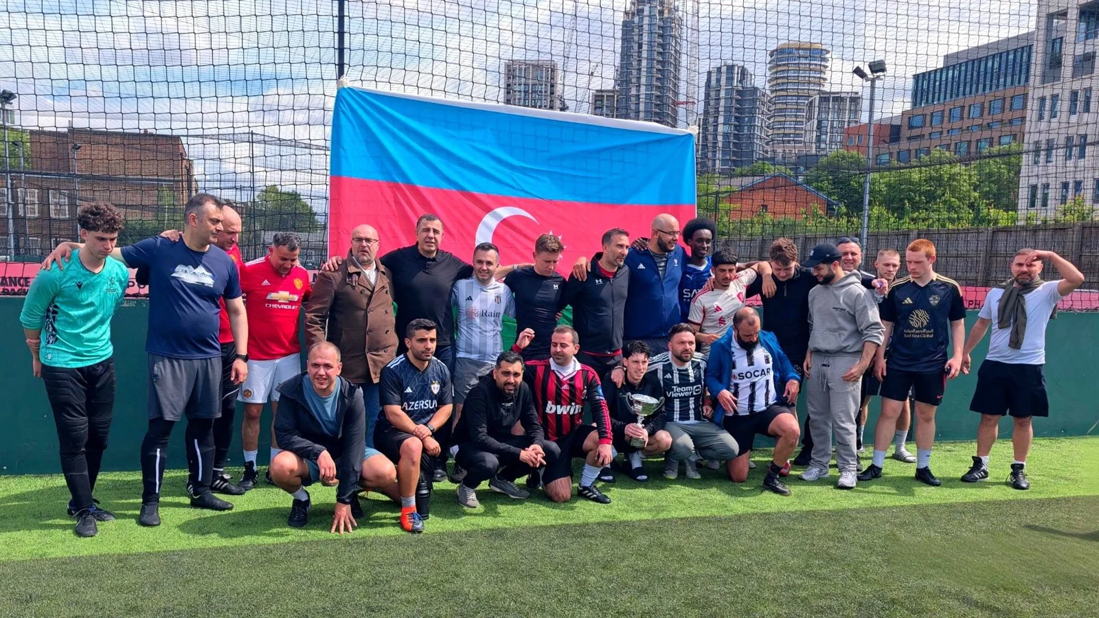 Community football players posing together beside a pitch